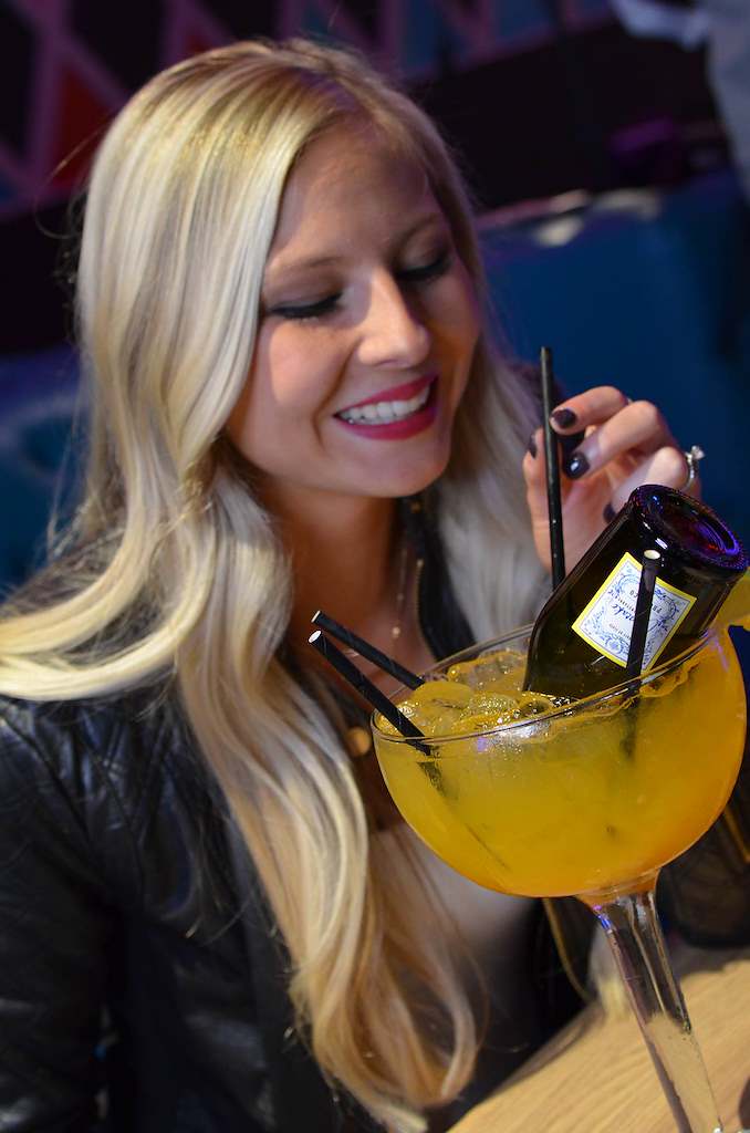 Guest enjoying a signature fishbowl cocktail at PINZ